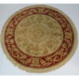 A late 20thC buff ground circular silk rug with rouge border. 84" diameter CONDITION: Please Note -