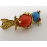 A gilt metal brooch formed as a bird on a perch, the bird with red and blue cabochon decoration