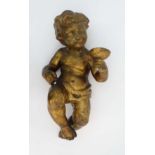 A large gilt Majolica putto holding a wine goblet, in a Bacchus like pose. Probably a candle holder.