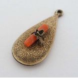 A gilt metal pendant of drop form set with coral and leaf decoration. 1 1/8" long 
 CONDITION: