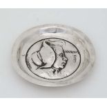 A silver dish with embossed decoration depicting a young girl wearing a bonnet titled Nancy and a