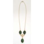 A yellow metal necklace set 3 carved jade cabochon and central floral detail . Approx 15” long