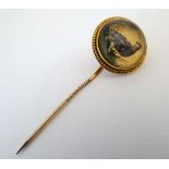A gilt metal stick pin surmounted by an Essex crystal cabochon depicting an English partridge in a
