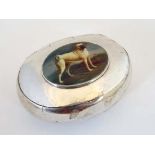 A white metal snuff box of ovoid form with later applied ceramic cabochon to lid depicting a dog