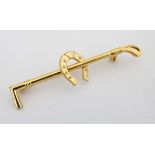 A gilt metal brooch / stock pin formed as a riding crop with horseshoe decoration to centre. 2 ¼"