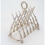 A late 20thC silver plate novelty 7 bar toast rack, the divisions formed as crossed guns , with