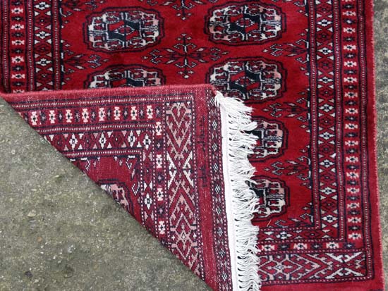 Rug / Carpet : a woollen Bokhara runner with 26 roundels to centre on a wine red back ground with - Image 2 of 6