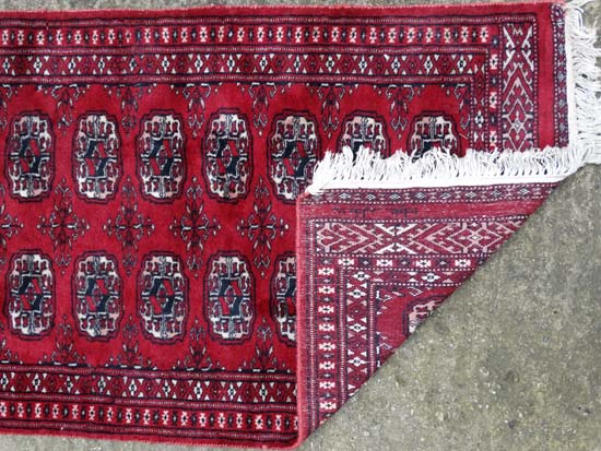 Rug / Carpet : a woollen Bokhara runner with 26 roundels to centre on a wine red back ground with - Image 6 of 6