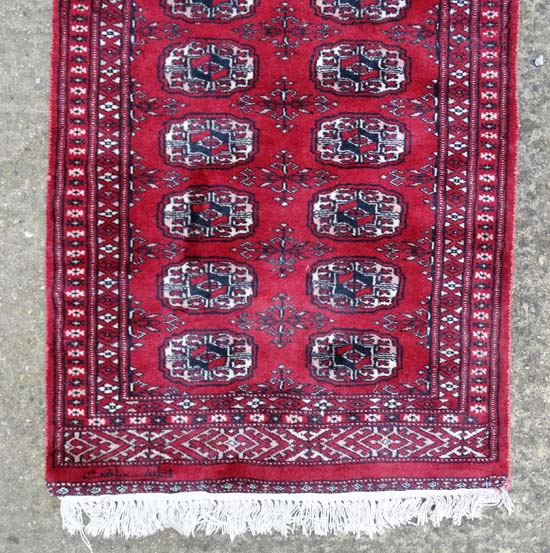 Rug / Carpet : a woollen Bokhara runner with 26 roundels to centre on a wine red back ground with - Image 3 of 6