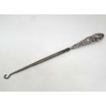 An embossed white metal button hook CONDITION: Please Note -  we do not make reference to the
