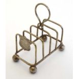 A silver plate 5 bar toast rack with shield shaped cartouche bearing inscription ' Presented by