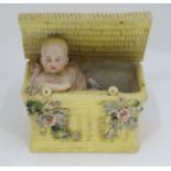 A ceramic bisque figure of a Baby in basket  CONDITION: Please Note -  we do not make reference to