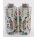 A pair of Chinese famille verte hexagonal lidded vases, hand painted in enamels with figures and