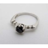 A 9ct white gold ring set with central black stone flanked by 2 diamonds to each shoulder.