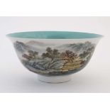 A Chinese famille rose bowl decorated with a figure boating on a lake amongst mountainous scenery,