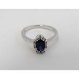 An 18ct white gold ring set with oval sapphire bordered by diamonds CONDITION: Please Note -  we