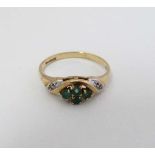 A 9ct gold ring set with four emeralds flanked by chip set diamond to shoulders.  CONDITION: