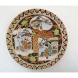 A small handpainted Japanese plate decorated in shades of green and red with gilt highlights , the