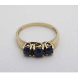 A yellow metal ring set with three graduated blue stone cabochon CONDITION: Please Note -  we do not