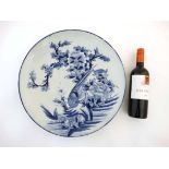 A large Chinese blue and white charger decorated with an exotic bird on a rocky outcrop amongst