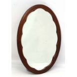 An Edwardian oval wall mirror with checkered inlay to the mahogany cloud shaped surround 32" x