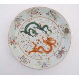 A  Chinese famille rose charger decorated with a green and a red five claw dragon fighting over a