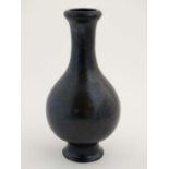 A Chinese flared rim bottle vase on a flared  with black salt glaze finish on a waisted circular