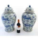 A large pair of Chinese blue and white lidded vases decorated with Dogs of Fo and pearls of wisdom