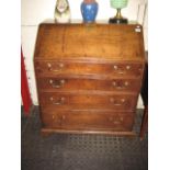 AN OAK BUREAU having a fall front enclosing an interior fitted with pigeon holes, drawers and