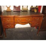 AN INLAID MAHOGANY SERPENTINE FRONT WRITING TABLE fitted with a long kneehole drawer and two short