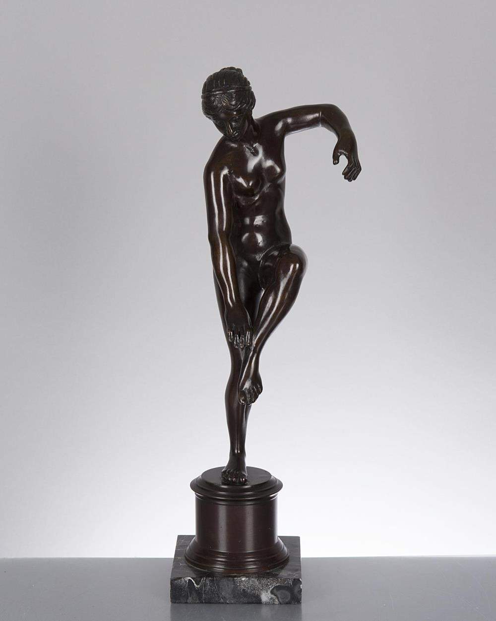 sculpture en bronze à patine médaille d'une jeune femme sur un pied se touchant la cheville de l'