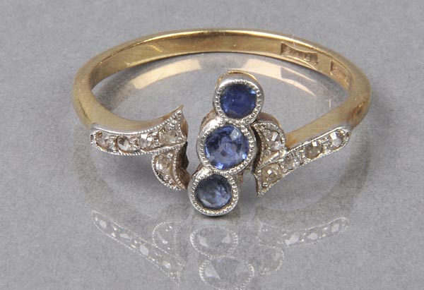 * Ring. A sapphire and diamond ring set in gold with three small aligned sapphires with flanked by
