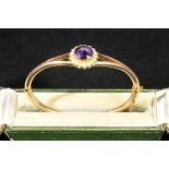 *Amethyst. An Edwardian yellow metal bangle,  set with a circular facet cut stone surrounded by