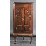*Corner Cabinet. An early 19th-century mahogany cabinet on stand,  with two arched panelled doors,