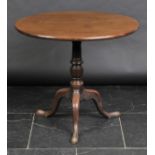 *Table. A George III mahogany tilt top table,  the circular top above turned pedestal on three