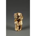 A JAPANESE IVORY FIGURE GROUP NETSUKE attributed to Hidemasa, showing a man and two boys playing,