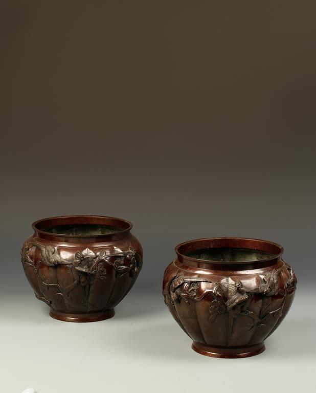A PAIR OF JAPANESE BRONZE JARDINIERES of segmented form, decorated with birds in a garden landscape,