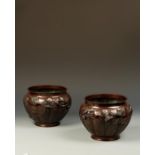 A PAIR OF JAPANESE BRONZE JARDINIERES of segmented form, decorated with birds in a garden landscape,