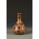 AN UNUSUAL ENAMELLED STONEWARE BOTTLE VASE decorated with flowerheads and tendrils in iron red and