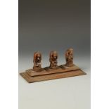 AN INDIAN WOOD CARVING OF THE THREE MYSTIC MONKEYS, each seated on rocks beside flowers, one