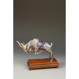 A CHINESE SILVER AND ENAMEL GOAT, the animal charging forward, wearing an ornate saddle with