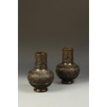 A PAIR OF JAPANESE ORNATE BRONZE VASES, the long necks and rounded bodies decorated with panels of