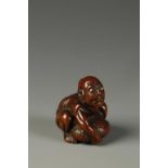 A JAPANESE WOOD NETSUKE OF A STONE LIFTER, the muscular figure crouching low to lift his load,