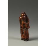 AN EARLY JAPANESE WOOD NETSUKE by Hachigyoku, showing Kanu standing upright and stroking his