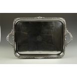 AN EDWARDIAN TWO HANDLED TRAY, the raised border with gadrooned and shell decoration borders, with