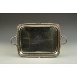 AN EDWARDIAN TWO HANDLED TRAY of shaped rectangular form with gadrooned and shell borders, with "D-