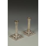 A PAIR OF LATE VICTORIAN CANDLESTICKS of column form with leaf capitals, the square bases