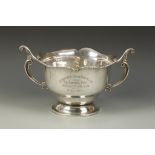 AN EDWARDIAN PRESENTATION BOWL of shaped circular form, with a wavy border and scroll handles, on