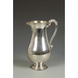 AN IRISH BEER JUG in the George III style, of baluster form with leaf capped scroll handle,