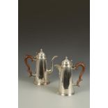 A PAIR OF CAFE AU LAIT POTS of tapering circular form, the hinged domed lids with knop finials,